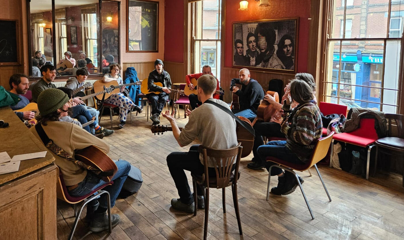 Guitar Workshop - Sheffield Sessions Festival 2026 A photo of ten guitarists sat in a circle. Credit: Rhi Good